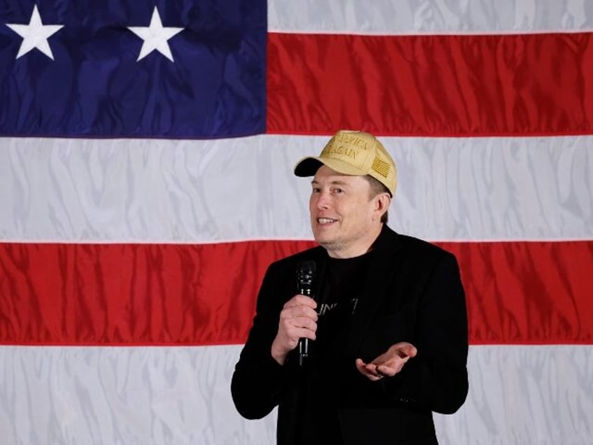 Elon Musk standing in front of a flag