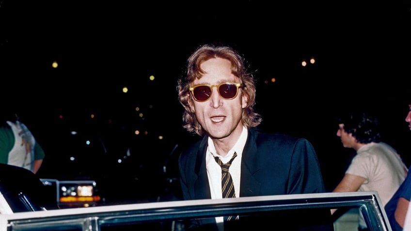 John Lennon wearing sunglasses getting into a car