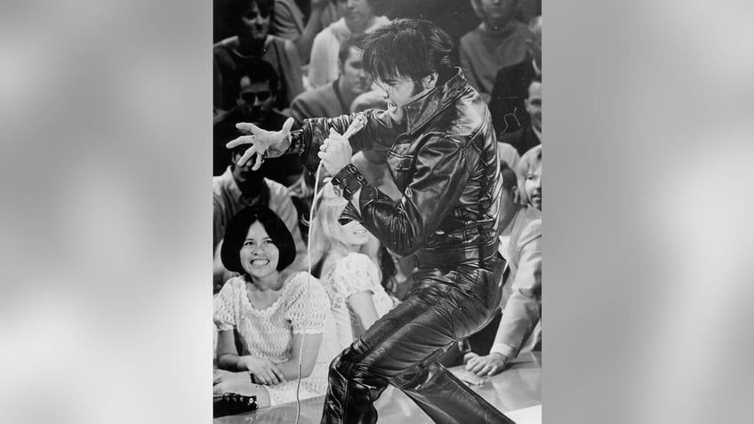 Elvis Presley performing on stage in his leather suit.