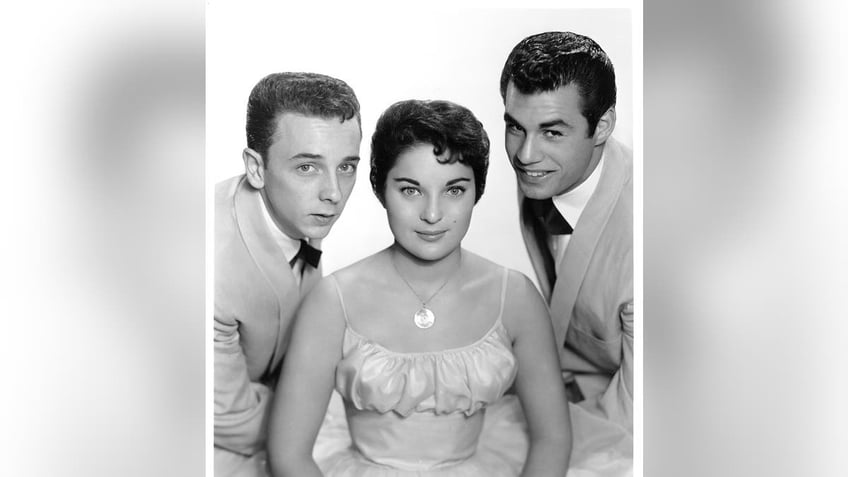 Carol Connors in between her bandmates of the Teddy Bears wearing a spaghetti strap dress.