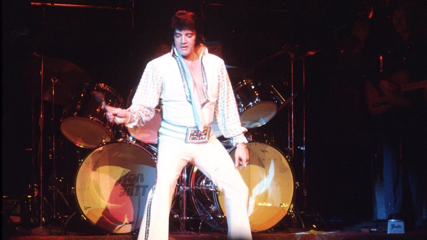 Elvis Presley performing on stage wearing a jumpsuit