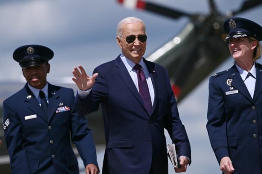 US President Joe Biden (C) is welcomed by Air Force Colonel Angela Ochoa (R) as he arrives