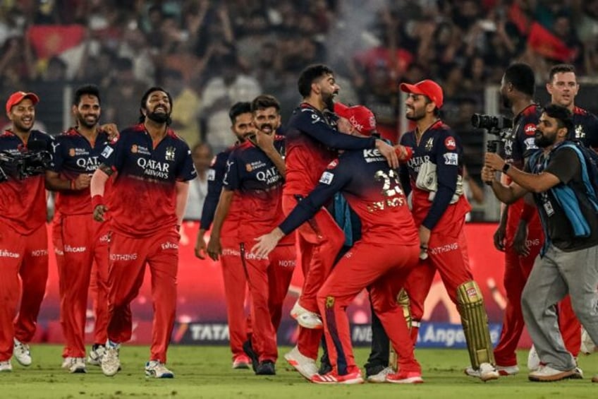 Virat Kohli (C) is mobbed by his teammates after Royal Challengers Bengaluru won their fir