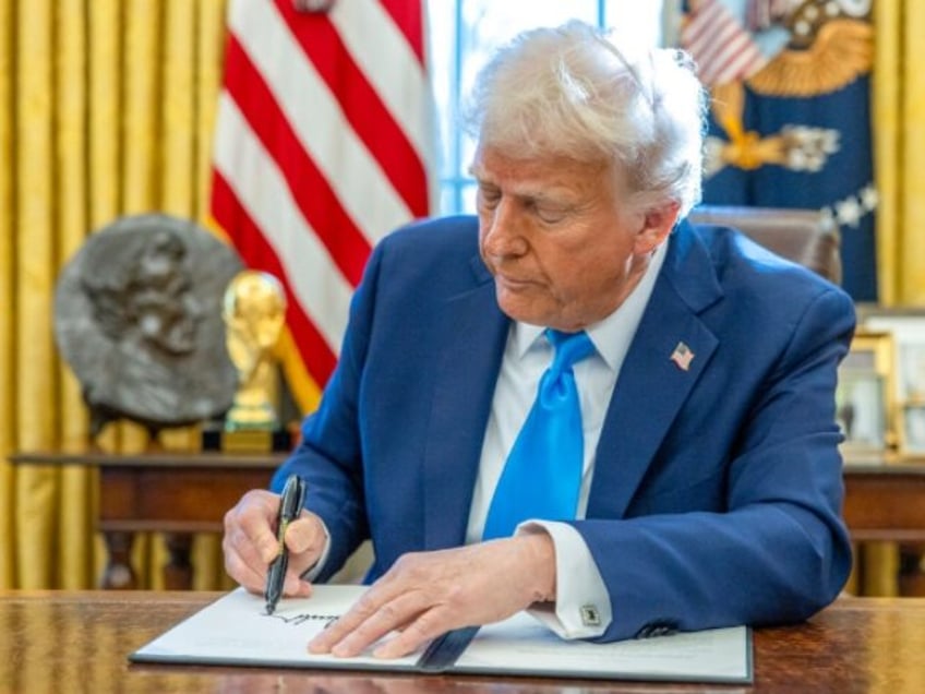 US President Donald Trump signs an executive order in the Oval Office of the White House i