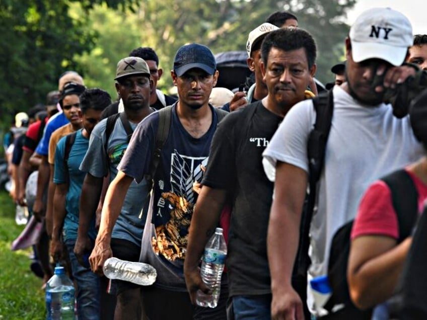 Migrants, mostly from Central America and Venezuela, walk towards the United States on the