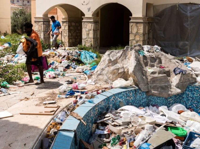 Asylum seekers walk amidst waste at the Ayios Nikolaos apartment complex, in Chloraka, a v