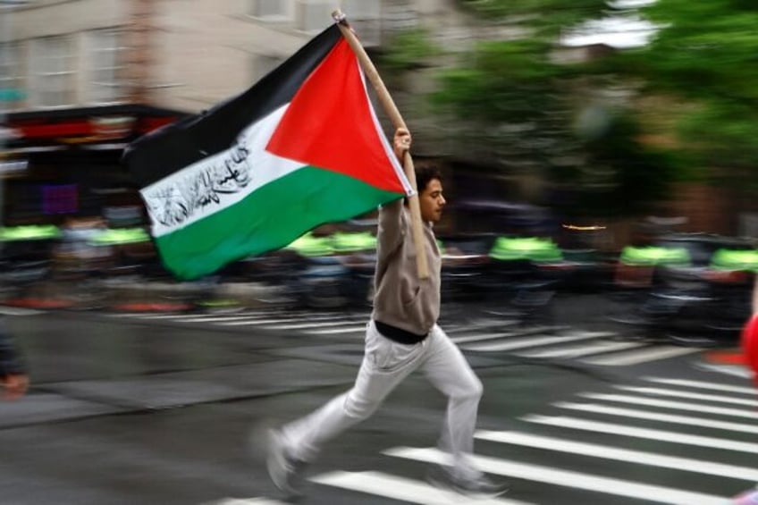 A pro-Palestinian demonstrator runs with a Palestinian flag during a rally in New York ear