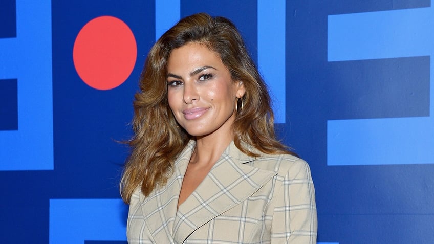 Eva Mendes in a plaid sand colored blazer soft smiles on the carpet