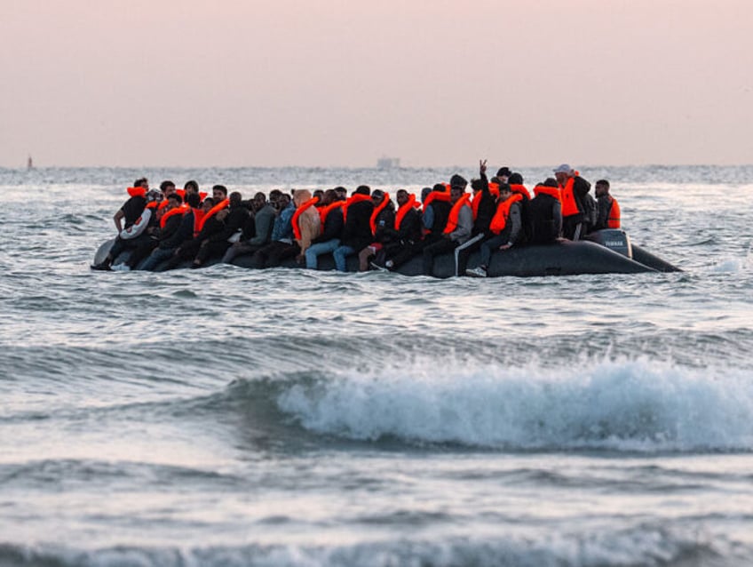 GRAVELINES, FRANCE - JULY 10: A man gestures from a migrant dinghy as it prepares to sail