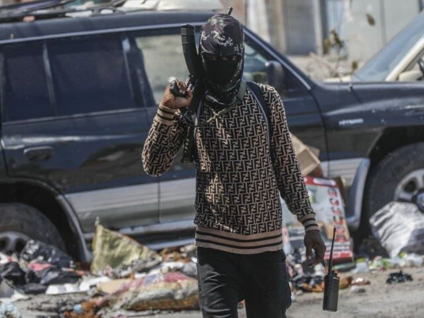 An armed member of the G9 and Family gang patrols a roadblock in the Delmas 6 neighborhood