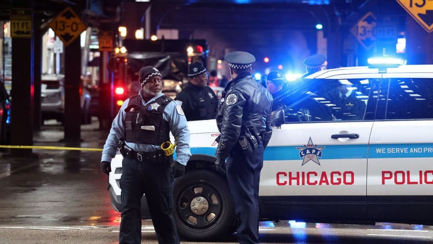 Chicago police at night at crime scene standing by cruiser