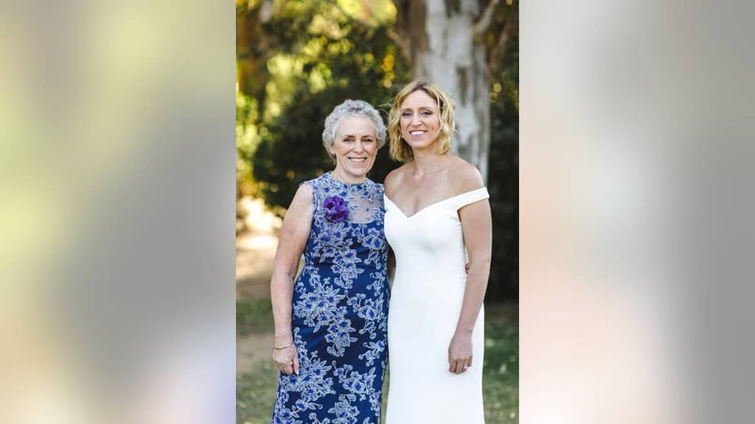 Mother and daughter pose wearing dresses in front of large tree