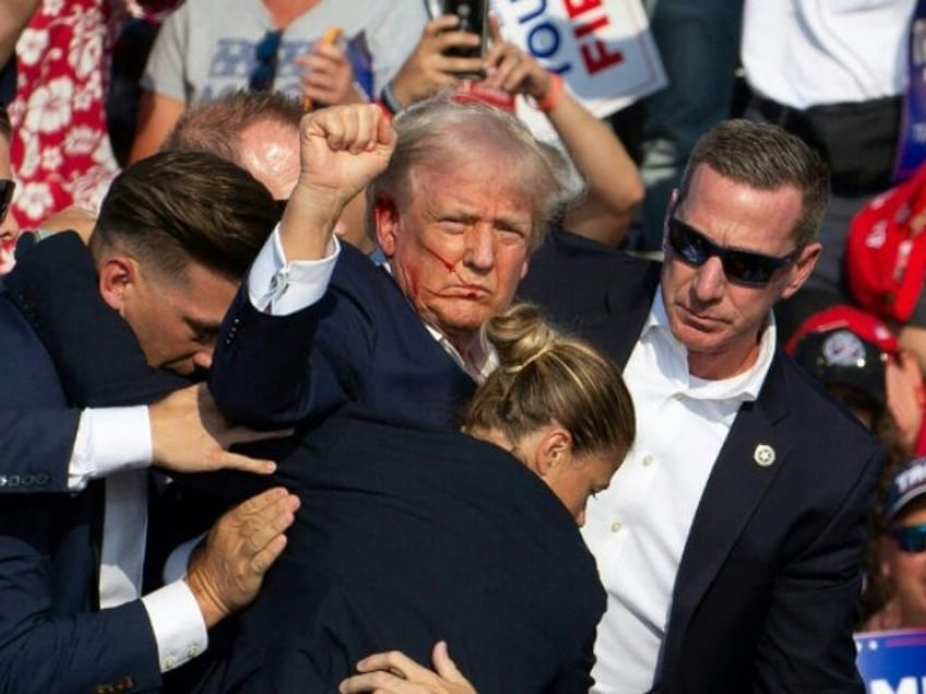 Republican candidate Donald Trump is seen with blood on his face surrounded by secret serv