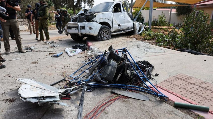 Israeli soldiers and journalists gather around a damaged powered paraglider used by Hamas terrorists in Kfar Aza, south of Israel bordering the Gaza Strip, on Oct. 10, 2023.