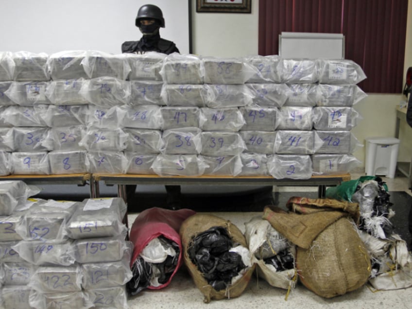 In this Oct. 8, 2013 photo, a Dominican anti-drug police officer stands behind packages of seized drugs during a news conference at the National Drug Control Agency in Santo Domingo, Dominican Republic. The Dominican Republic is now the region’s biggest transit point for drugs. A U.S. military assessment projected that 6 percent of the cocaine destined for the U.S. this year will pass through the Dominican Republic alone. (AP Photo/Manuel Diaz)