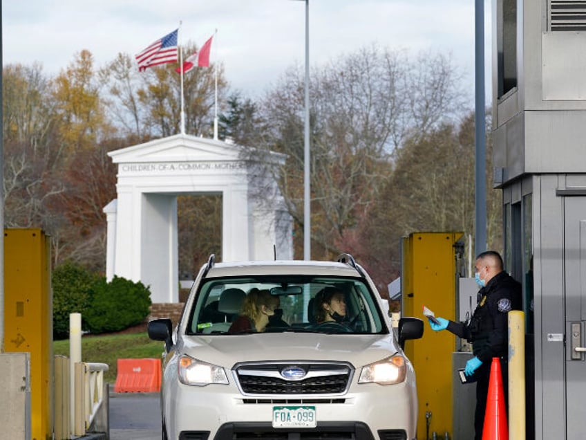 A U.S. Customs and Border Protection officer checks identification on a driver and passeng