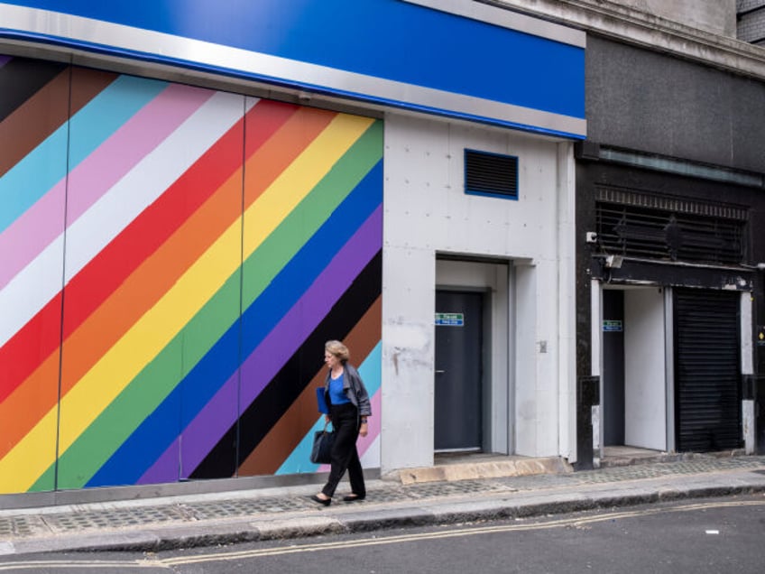 People interact with a large wall outside a high street bank emblazoned with the colours o