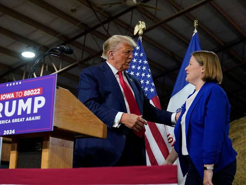 Former President Donald Trump talks with Iowa Attorney General Brenna Bird during a commit to caucus rally, Monday, Oct. 16, 2023, in Adel, Iowa. (AP Photo/Charlie Neibergall)