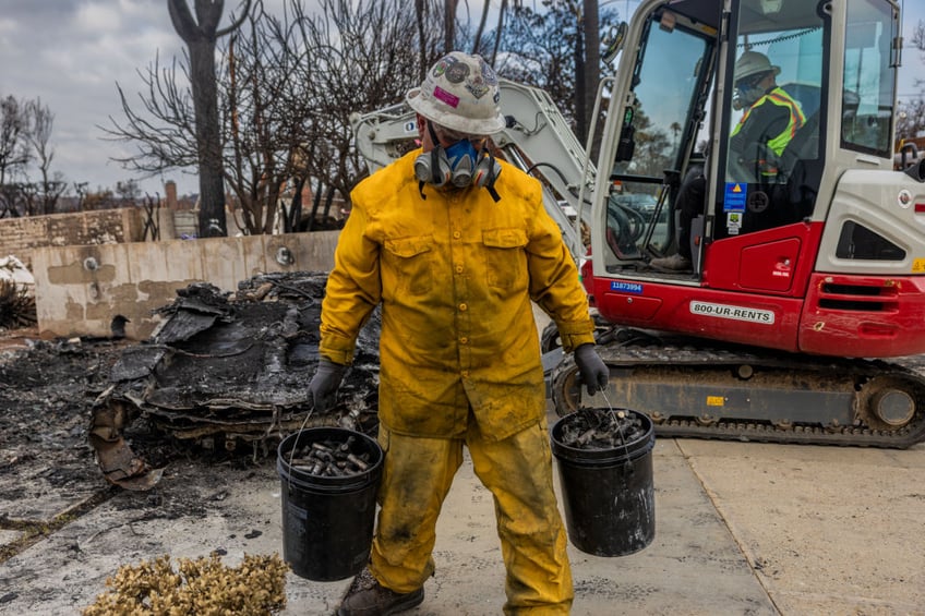 A worker with the US Environmental Protection Agency (EPA) holds buckets of burned lithium-ion batteries removed from a burned electric vehicle (EV) after the Palisades Fire in the Pacific Palisades area of Los Angeles, California, US, on Thursday, Jan. 30, 2025. The EPA has been tasked with removing toxic waste from over 16,000 homes and businesses destroyed in the Los Angeles wildfires within 30 days, a challenge that is testing the government's wildfire playbook. Photographer: Roger Kisby/Bloomberg via Getty Images