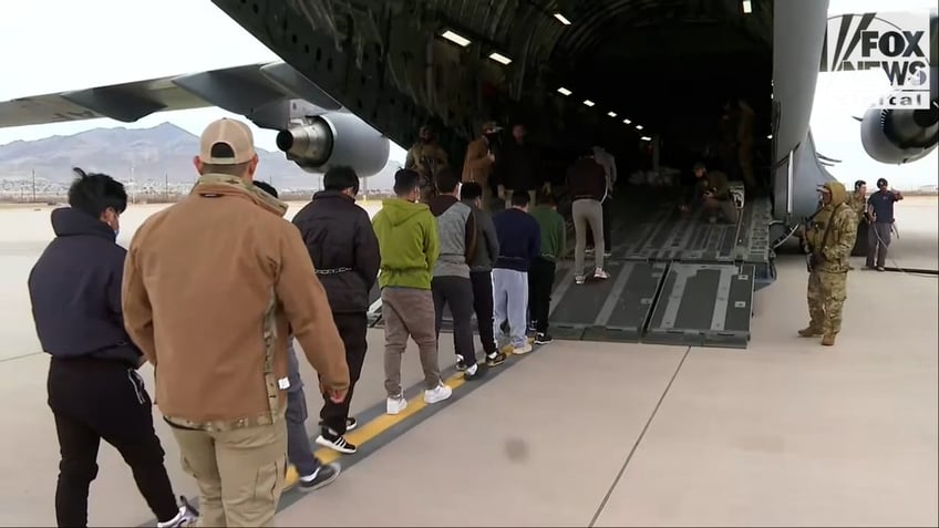 row of people walking into military plane