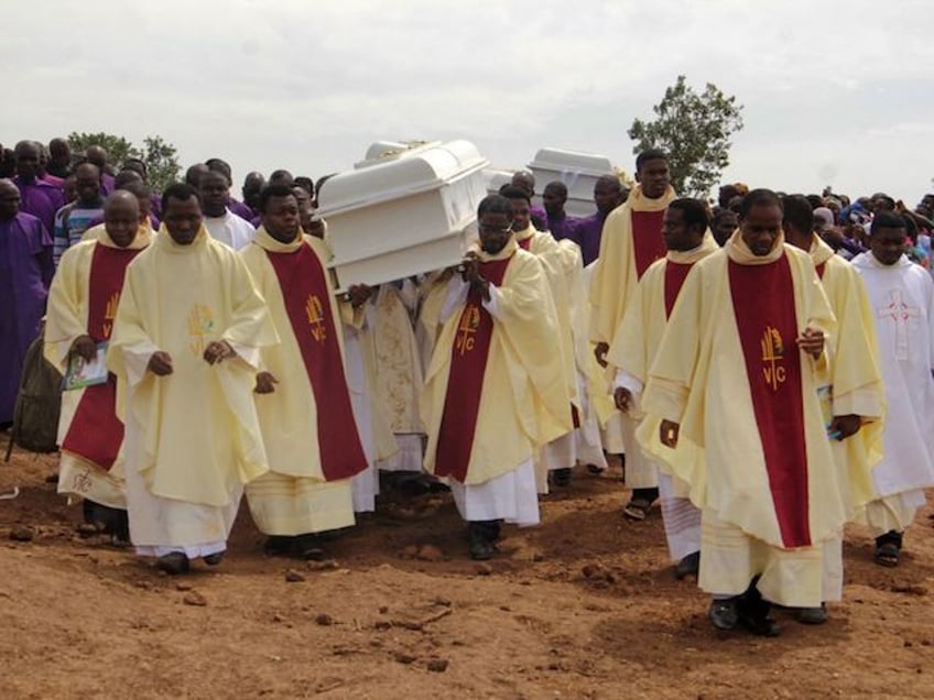 TOPSHOT - Clergymen carry white coffins containing the bodies of priests allegedly killed by Fulani herdsmen, for burial at Ayati-Ikpayongo in Gwer East district of Benue State, north-central Nigeria on May 22, 2018. - Two Nigerian priests and 17 worshippers have been buried, nearly a month after an attack on their church, as Catholics took to the streets calling for an end to a spiral of violence. White coffins containing the bodies of the clergymen and the members of their congregation were laid to rest in central Benue state, which has been hit by a wave of deadly unrest. (Photo by EMMY IBU / AFP) (Photo by EMMY IBU/AFP via Getty Images)