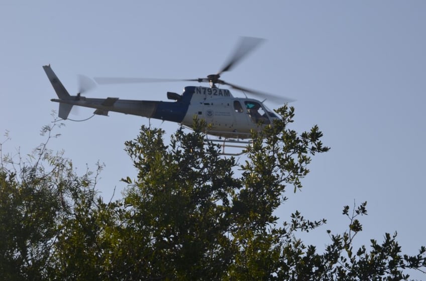 A CBP AMO A Star helicopter hovers over the trees in South Texas while searching ranchlands for migrants. (FILE: Bob Price/Breitbart Texas)