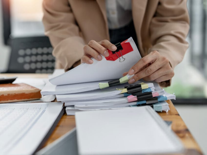 Bureaucrat, Businesswoman hands working on Stacks paper document files on her desk. Getty Images