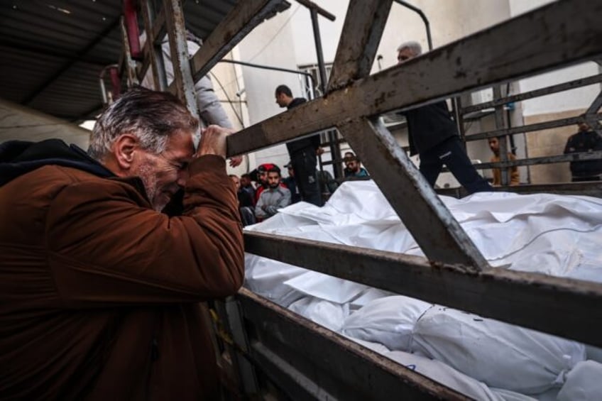 A man in Rafah mourns over the shrouded bodies of loved ones killed during an Israeli bombardment