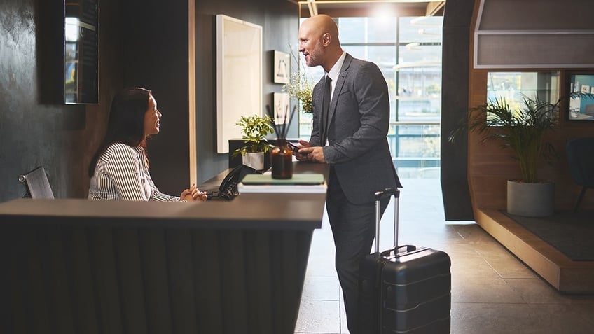 Man checks into a hotel at the front desk.