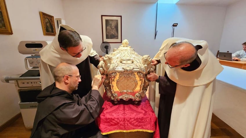 Priests and monk leaning over tomb