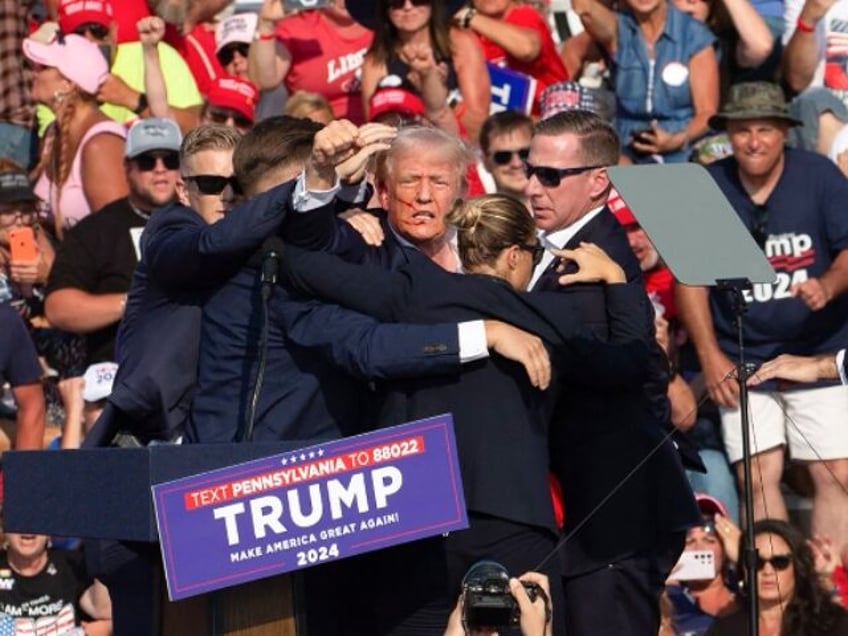 Republican candidate Donald Trump is seen with what appears to be blood on his face surrou