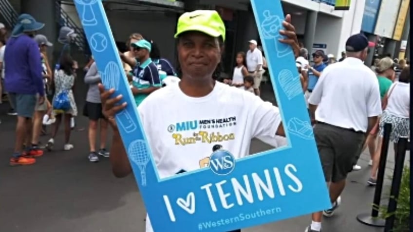 Stephen Singleton poses with a sign that says 'I love tennis'