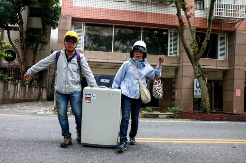 Residents carry their washing machine salvaged from the damaged Tongshuai Building followi