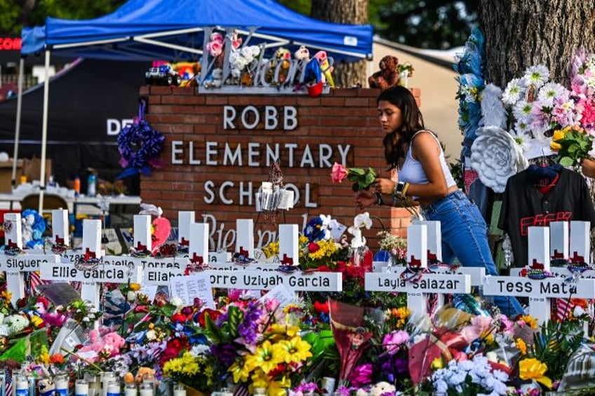 A girl lays flowers at a makeshift memorial at Robb Elementary School in Uvalde, Texas, on