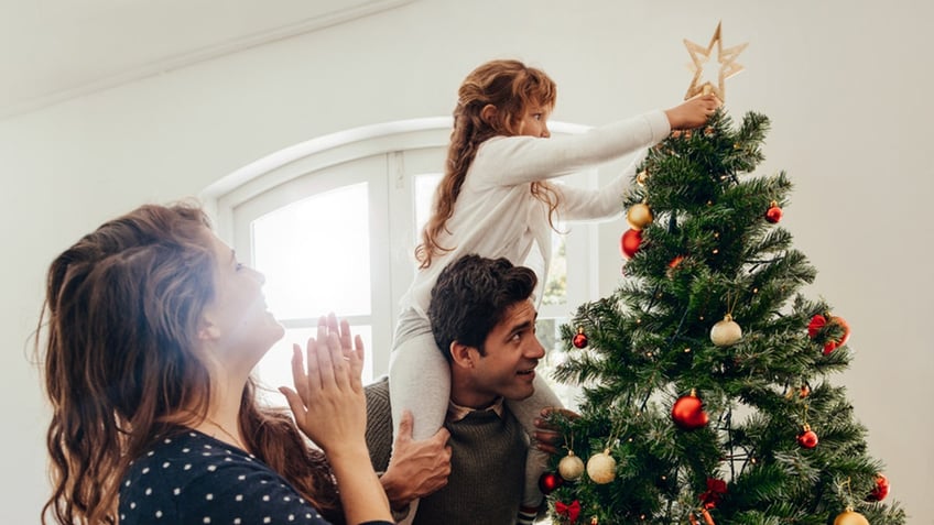 little girl putting on tree topper