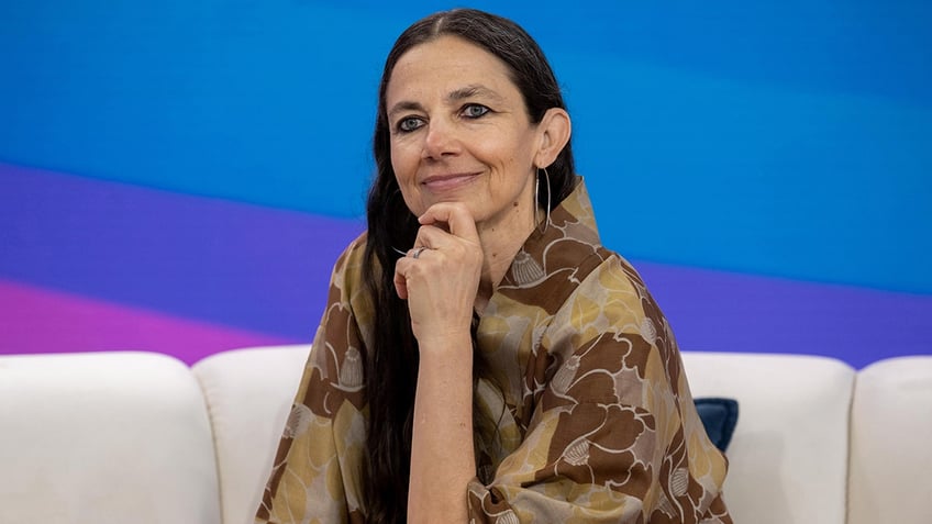 Justine Bateman puts her hand to her chin and soft smiles on the couch at the TODAY show