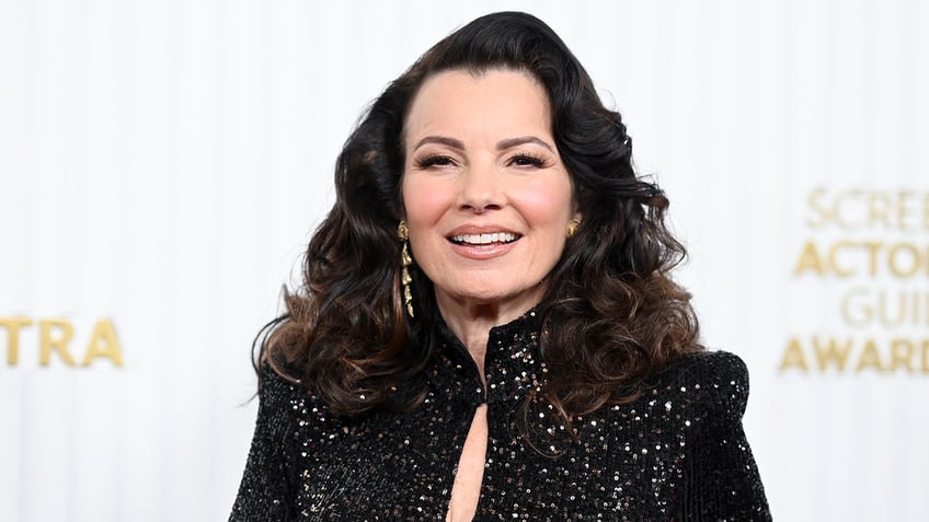 Fran Drescher smiles on red carpet while wearing glittering black dress