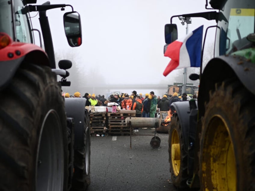 TOPSHOT - Farmers of the CR47 union (Coordination rurale 47), next to French flag on a tractor, attend a blocking of the A62 highway near Agen, southwestern France, on January 27, 2024, as part of a nationwide movement of protests called by several farmers' unions on pay, tax and regulations. …