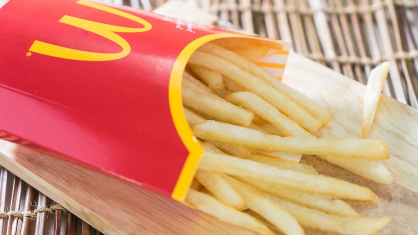 An order of McDonald's french fries rests on its side on a wooden tray.