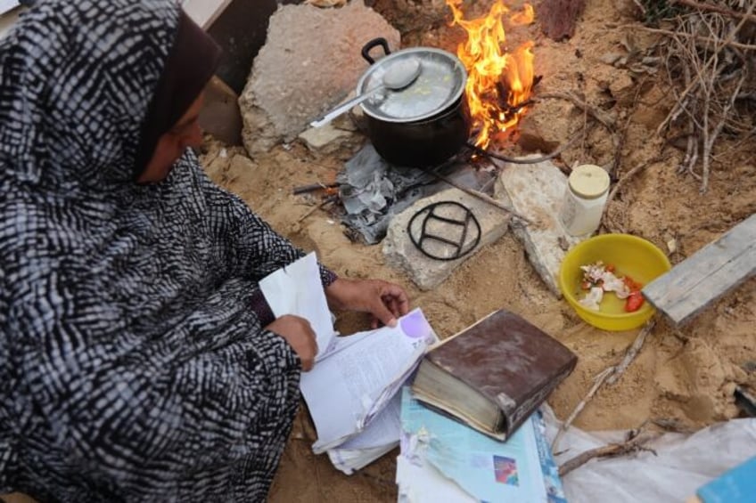 A displaced Palestinian burns pages of a book, collected from the destroyed Islamic Univer