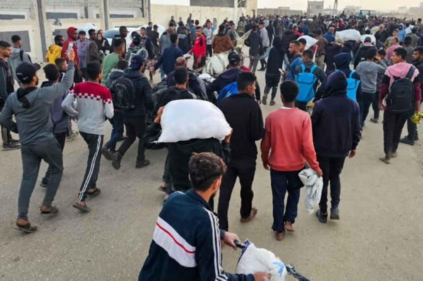 Displaced Palestinians, some carrying sacks of food, leave a distribution centre in Rafah,