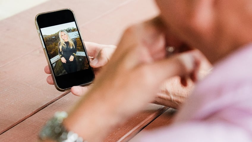 Stephen Federico looks at a photo of his daughter, Logan Federico, on his phone.