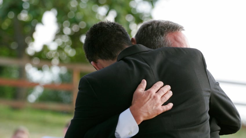 Two men hug each other. Horizontal with copy space.