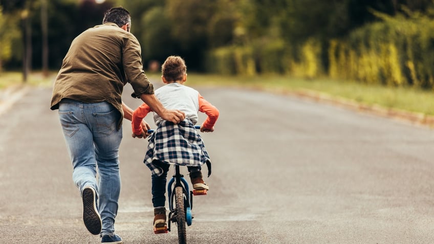 Dad teaching son bike ride