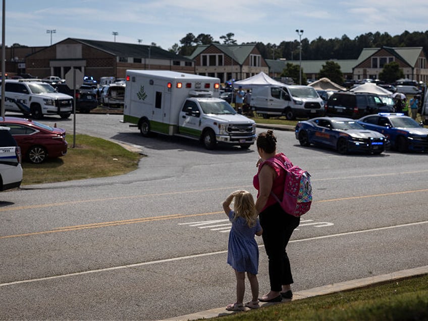 TOPSHOT - A young girl and her mother watch as law enforcement and first responders surrou