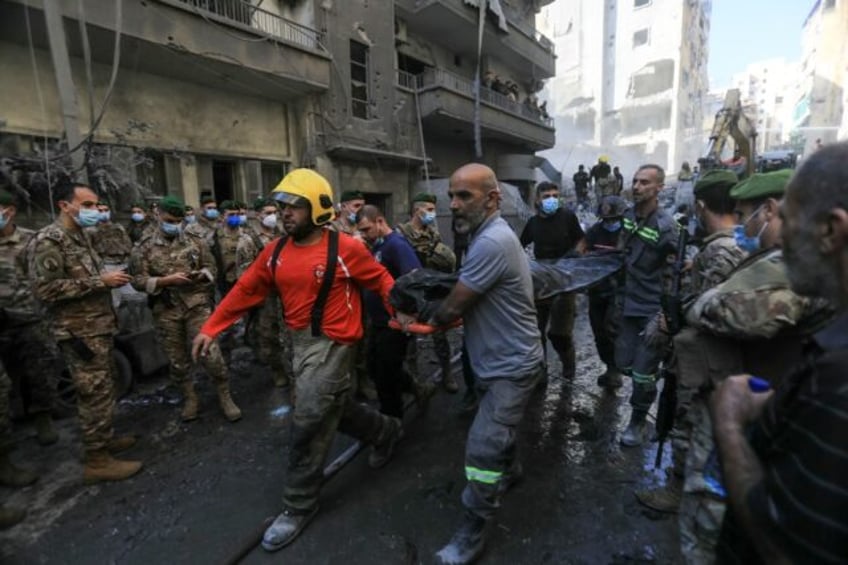 Lebanese soldiers look on as rescuers remove a body extracted from the rubble of a levelle