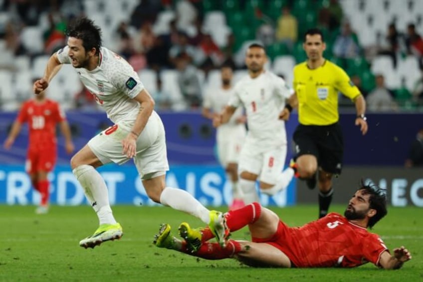 Palestine's defender #05 Mohammed Saleh tackles Iran's forward #20 Sardar Azmoun during the Qatar 2023 AFC Asian Cup Group C football match between Iran and Palestine