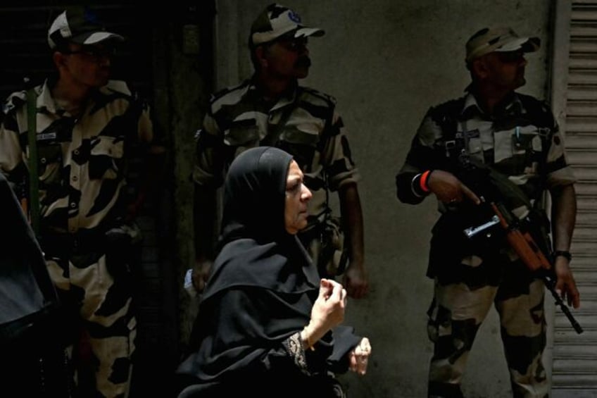 A Muslim woman walks past security personnel after casting her ballot to vote in Mumbai on