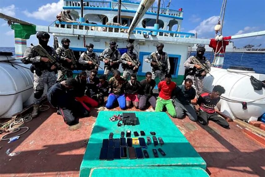 Indian commandos stand guard over Somali pirates who kidnapped an Iranian fishing vessel o