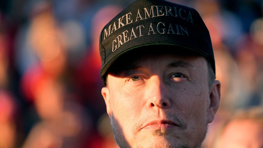 closeup shot of Elon Musk in blue and navy MAGA hat